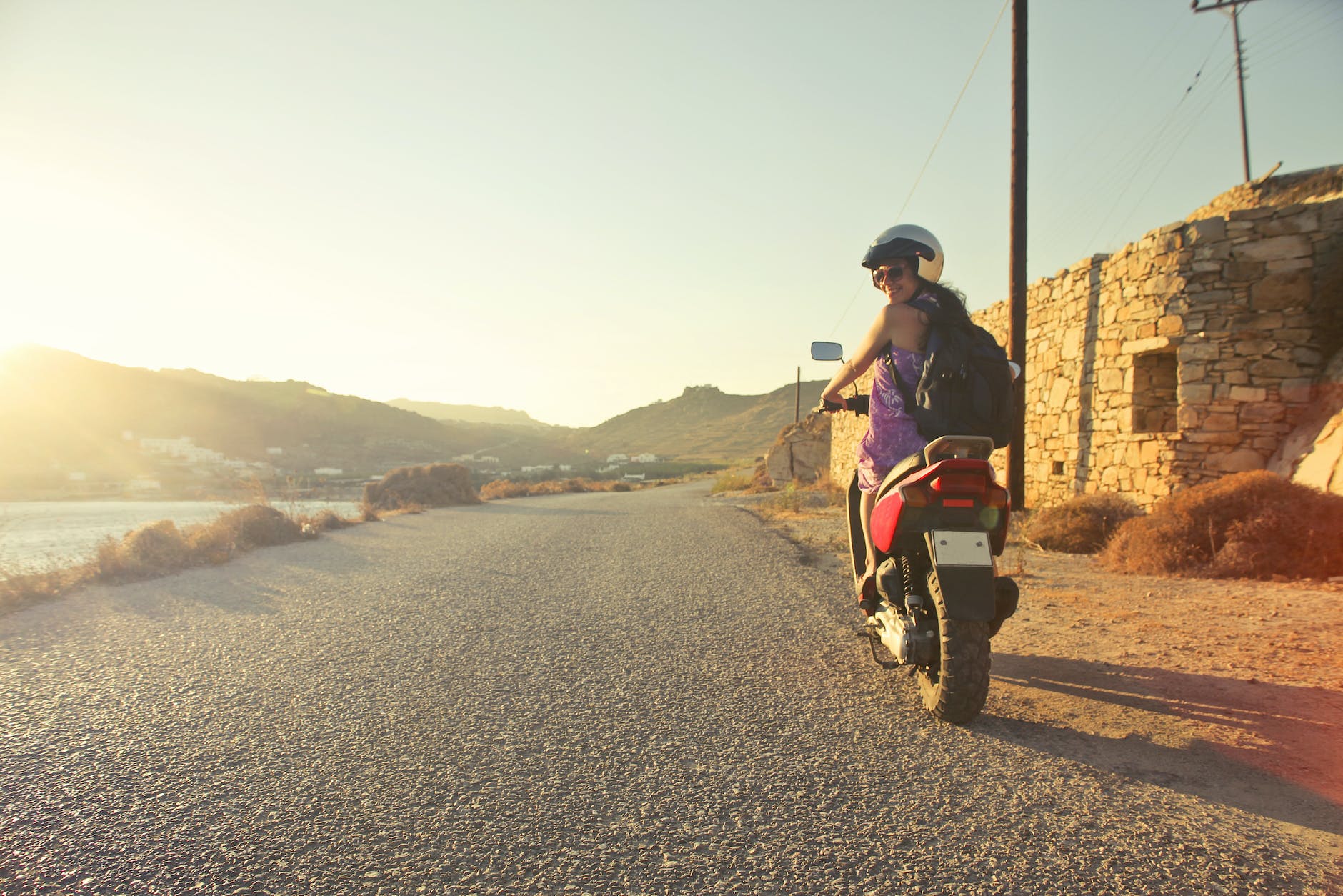 woman riding motor scooter travelling on asphalt road during sunrise